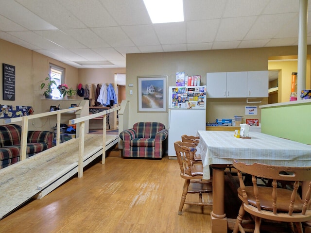 dining area with light wood-type flooring and a drop ceiling