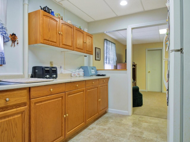 kitchen with a paneled ceiling and light colored carpet