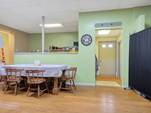 dining room featuring light wood-type flooring and a paneled ceiling