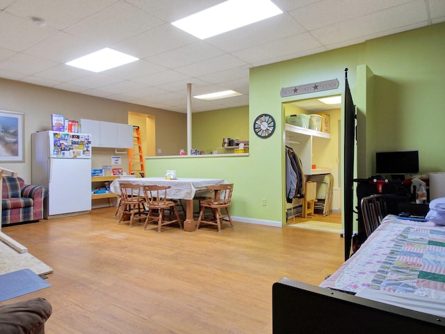 bedroom with white refrigerator, hardwood / wood-style flooring, and a drop ceiling