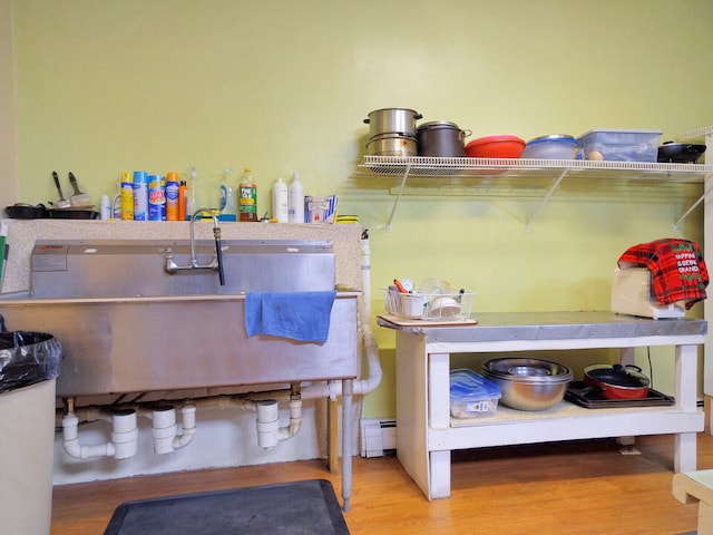 clothes washing area featuring a baseboard heating unit and hardwood / wood-style flooring