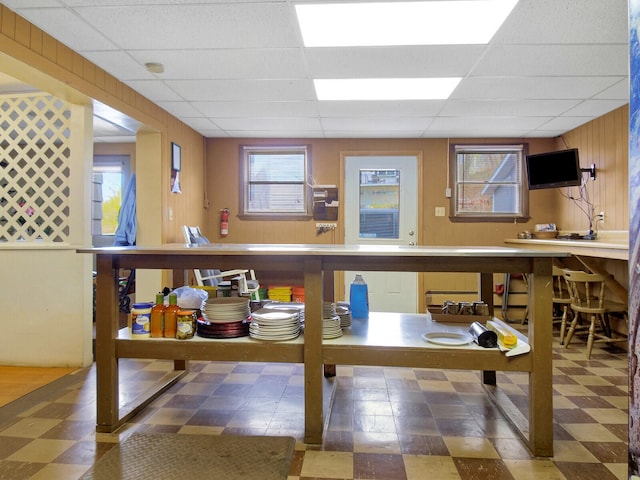 interior space with a paneled ceiling and wooden walls