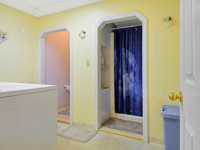 bathroom featuring washer / clothes dryer, walk in shower, and a drop ceiling