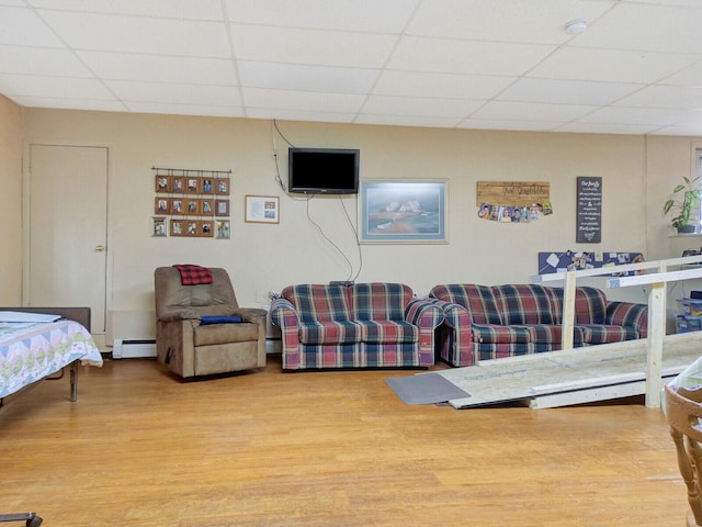 living room with a paneled ceiling, hardwood / wood-style flooring, and baseboard heating