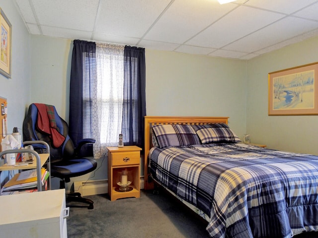 carpeted bedroom with a baseboard radiator and a drop ceiling