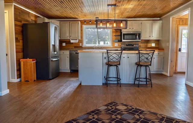 kitchen with stainless steel appliances, dark hardwood / wood-style floors, pendant lighting, a kitchen island, and a breakfast bar