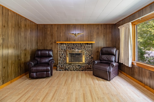 living area with wooden walls, a brick fireplace, and light wood-type flooring