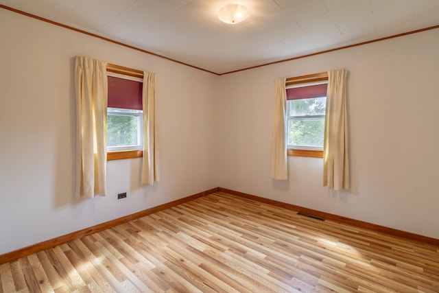 spare room with ornamental molding and light wood-type flooring