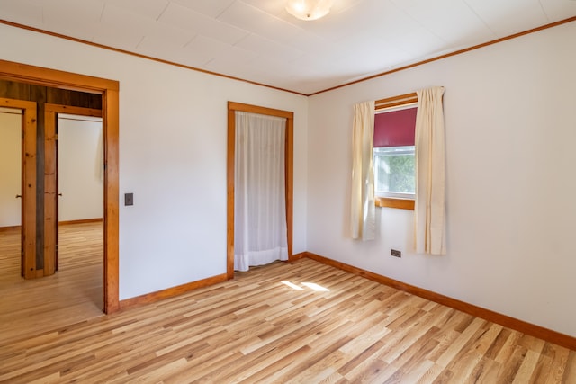 unfurnished bedroom featuring crown molding and light wood-type flooring