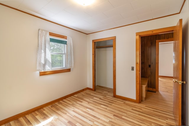 unfurnished bedroom with a closet, crown molding, and light hardwood / wood-style flooring