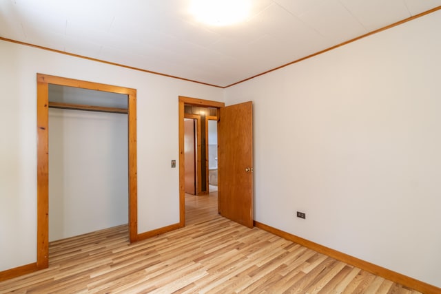 unfurnished bedroom featuring light hardwood / wood-style flooring, a closet, and crown molding