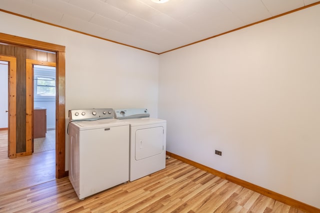 washroom with ornamental molding, washer and clothes dryer, and light wood-type flooring