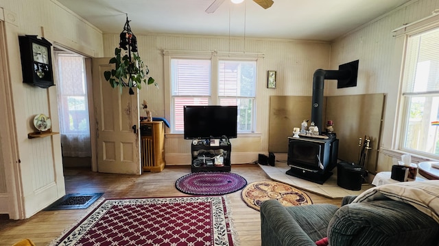 living room featuring visible vents, ornamental molding, wood finished floors, ceiling fan, and a wood stove