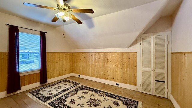 additional living space featuring lofted ceiling, wooden walls, hardwood / wood-style floors, and wainscoting