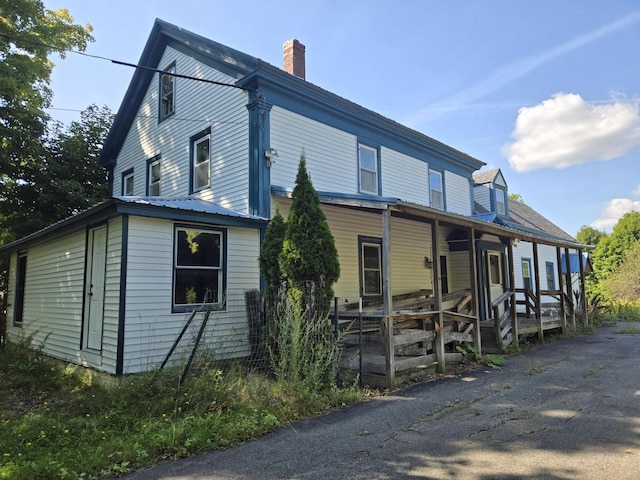 view of front of home featuring a porch and a chimney