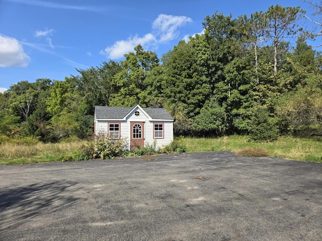 view of front of property featuring a shingled roof and an outdoor structure