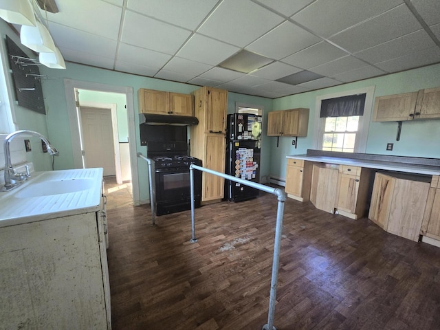 kitchen featuring dark wood-type flooring, black appliances, under cabinet range hood, a drop ceiling, and a sink