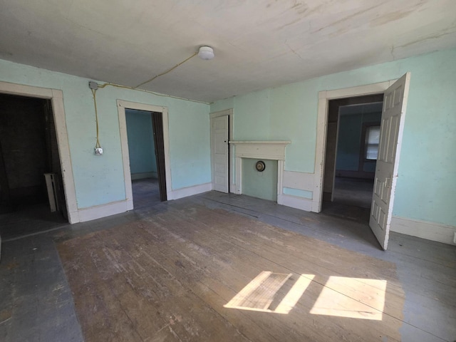 unfurnished living room featuring radiator heating unit, baseboards, and hardwood / wood-style floors