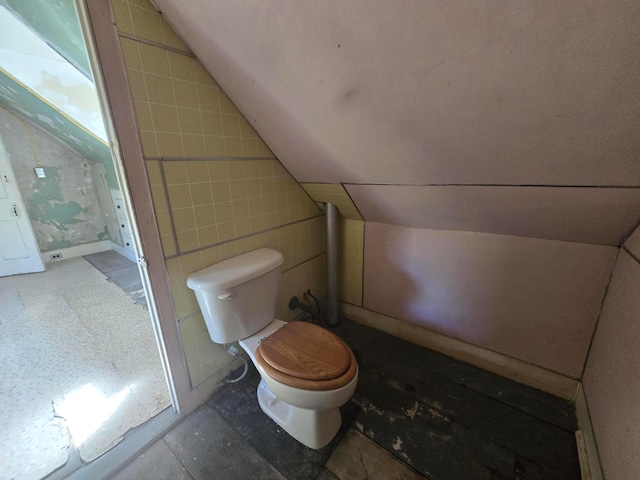 bathroom featuring lofted ceiling, tile walls, and toilet