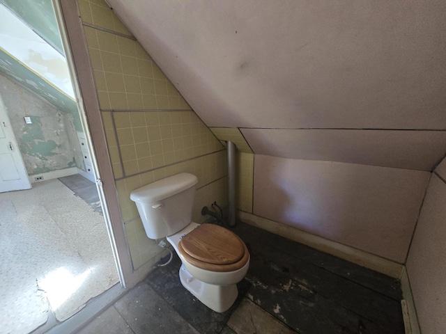 bathroom featuring toilet, tile walls, and vaulted ceiling