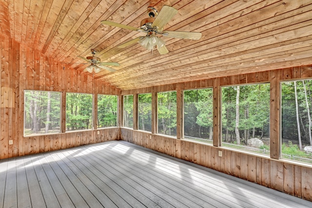 unfurnished sunroom featuring a healthy amount of sunlight, ceiling fan, and wooden ceiling