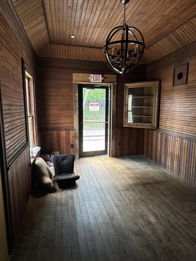 unfurnished room with wood walls, an inviting chandelier, lofted ceiling, and wood ceiling