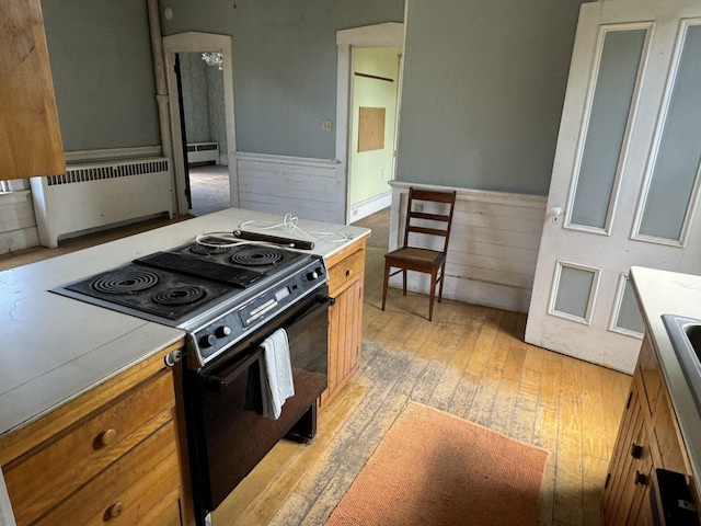 kitchen featuring radiator, electric range, and light hardwood / wood-style flooring