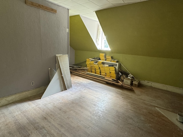 additional living space with wood-type flooring and vaulted ceiling