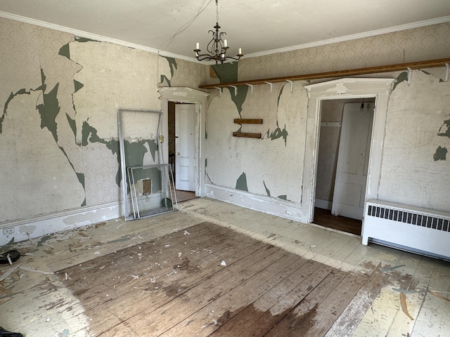 empty room with ornamental molding, radiator heating unit, wood-type flooring, and an inviting chandelier