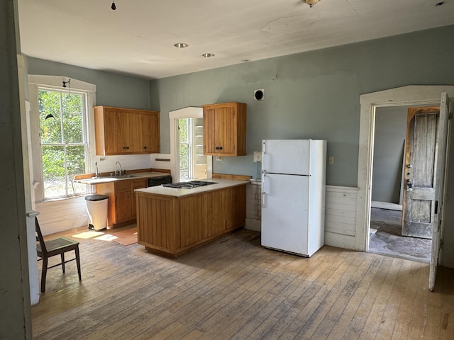 kitchen featuring kitchen peninsula, light wood-type flooring, gas stovetop, black dishwasher, and white fridge