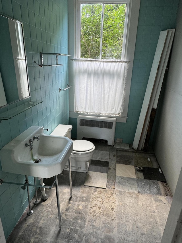 bathroom with radiator heating unit, tile walls, and toilet