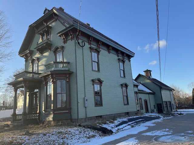 view of snowy exterior featuring covered porch and a balcony