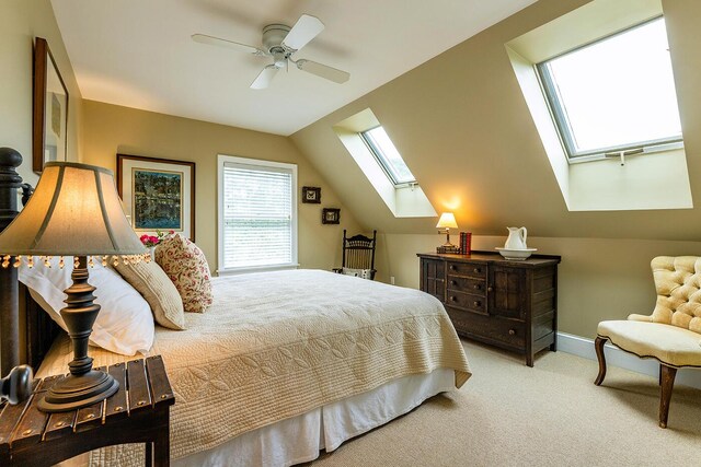 bedroom featuring lofted ceiling with skylight, light carpet, and ceiling fan