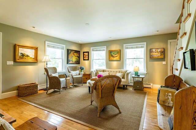 living room with light hardwood / wood-style flooring, baseboard heating, and a healthy amount of sunlight