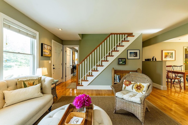 living room featuring stairs, baseboards, and wood finished floors