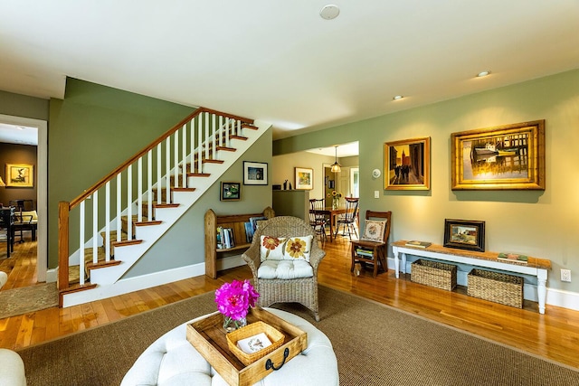 living area featuring stairway, wood-type flooring, and baseboards