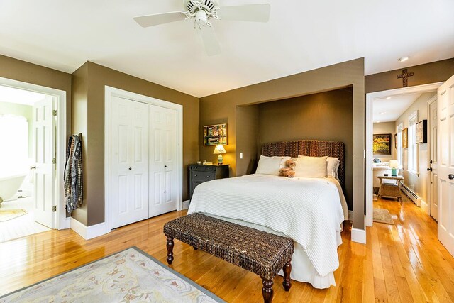 bedroom featuring light hardwood / wood-style flooring, a baseboard heating unit, and ceiling fan