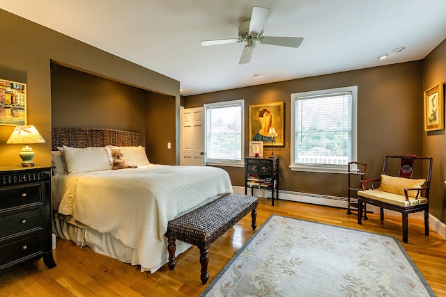 bedroom with a baseboard heating unit, ceiling fan, and hardwood / wood-style floors