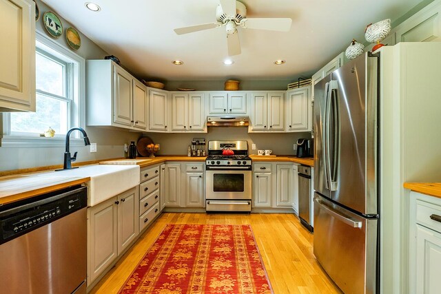 kitchen with white cabinets, butcher block counters, light hardwood / wood-style flooring, stainless steel appliances, and ceiling fan