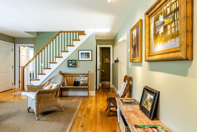 sitting room featuring light wood finished floors, stairs, and baseboards