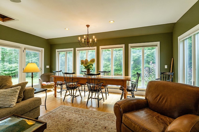 dining area with vaulted ceiling, light hardwood / wood-style flooring, and a chandelier