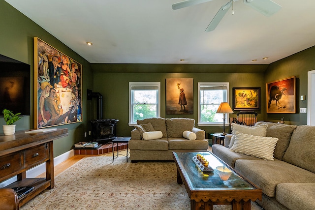 living room featuring light hardwood / wood-style floors, ceiling fan, and a wood stove