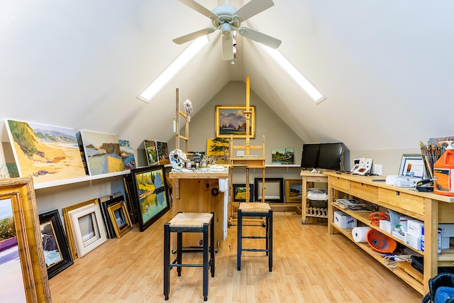 home office featuring light hardwood / wood-style flooring, ceiling fan, and lofted ceiling with skylight