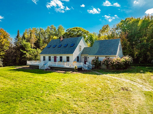 back of house featuring a lawn, a chimney, a deck, and roof with shingles