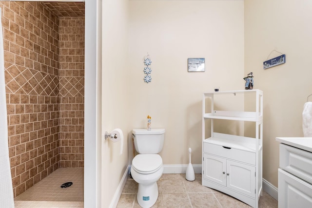 bathroom with tiled shower, vanity, toilet, and tile patterned flooring