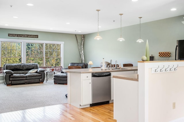 kitchen with light wood-type flooring, pendant lighting, stainless steel appliances, sink, and white cabinets