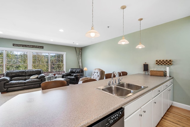 kitchen with light hardwood / wood-style flooring, decorative light fixtures, kitchen peninsula, sink, and white cabinets