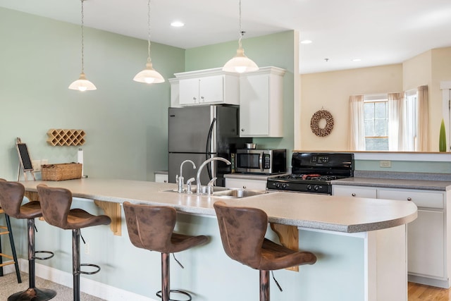 kitchen featuring pendant lighting, light hardwood / wood-style flooring, stainless steel appliances, a kitchen breakfast bar, and sink