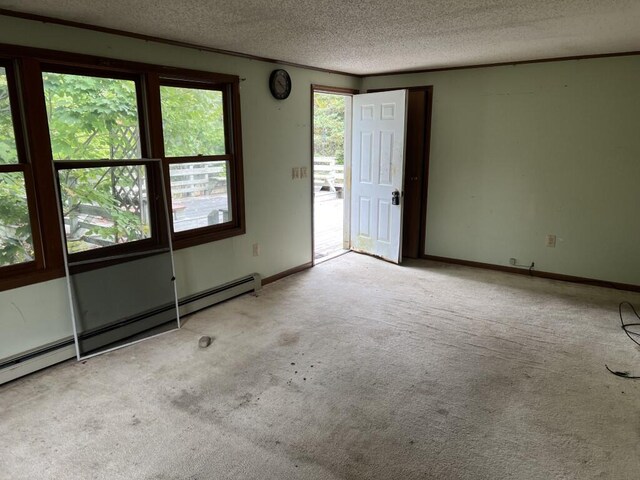 carpeted empty room featuring a baseboard radiator, a textured ceiling, and a wealth of natural light