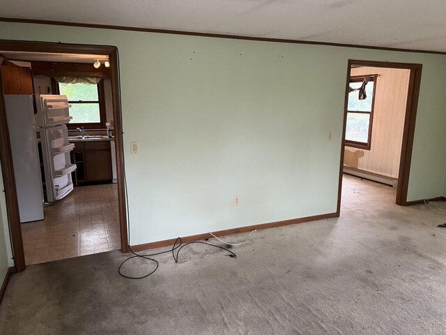 empty room with sink, carpet floors, and baseboard heating